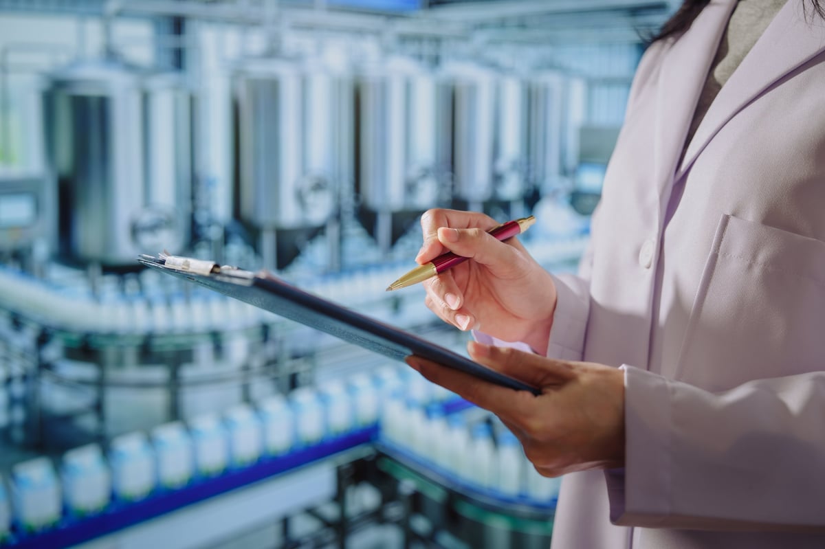 Quality control specialist with a tablet approving production standards in a modern food facility